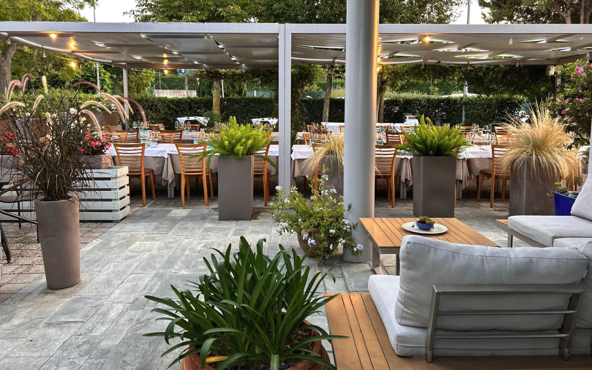 Una foto della sala da pranzo esterna del ristorante, con numerose piante e fiori